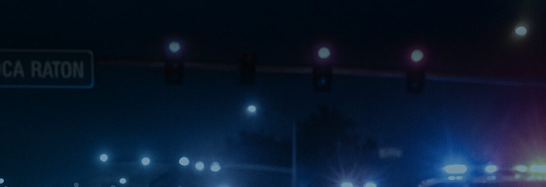 Traffic lights and emergency vehicle lights illuminating a nighttime scene in Boca Raton, highlighting the urgency of car accidents.